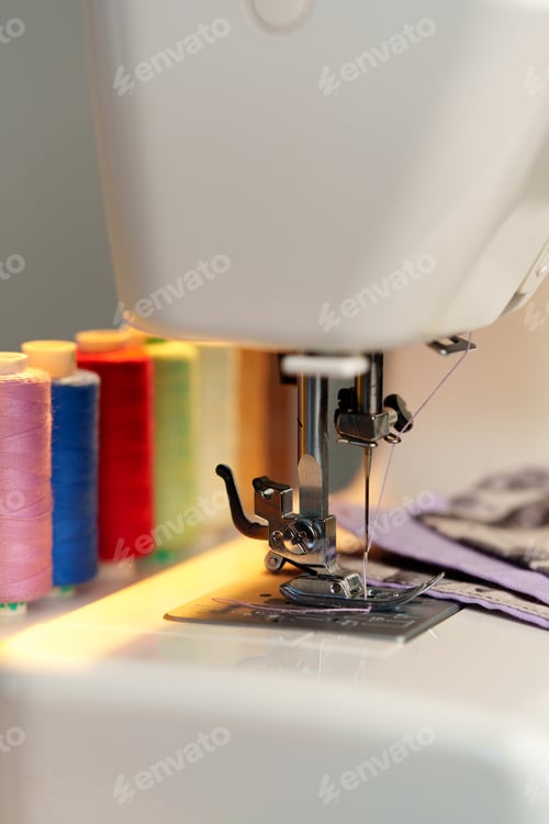 Preview: Colorful threads lined up beside a sewing machine ready for creative fabric projects