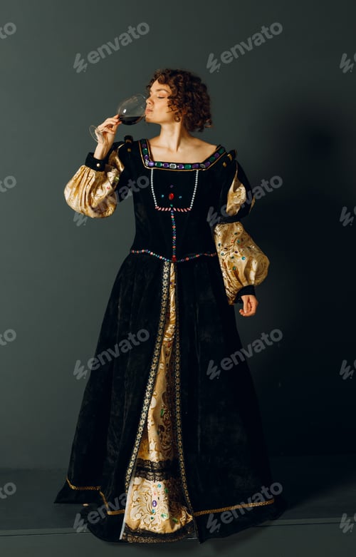 Vista previa: Young adult woman dressed in a medieval dress holding a glass of wine.