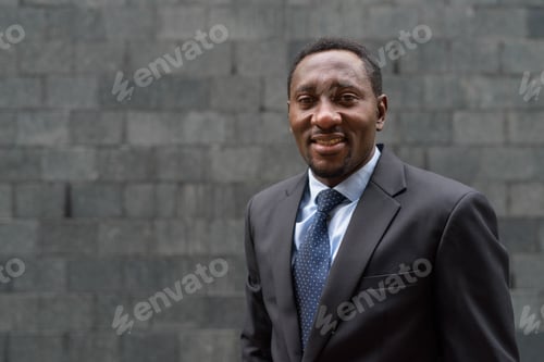 Preview: Portrait of handsome African businessman in city smiling