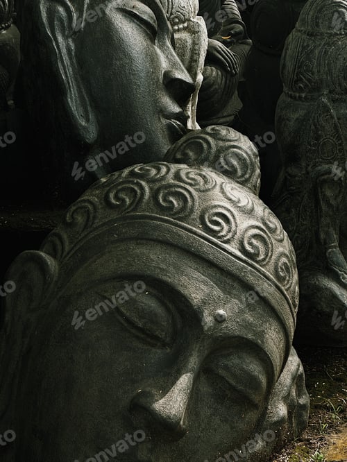 Preview: Closeup of Buddha statues on grass near trees.