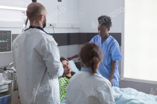 Preview: Sick woman resting in bed with nasal oxygen tube during medical appointment