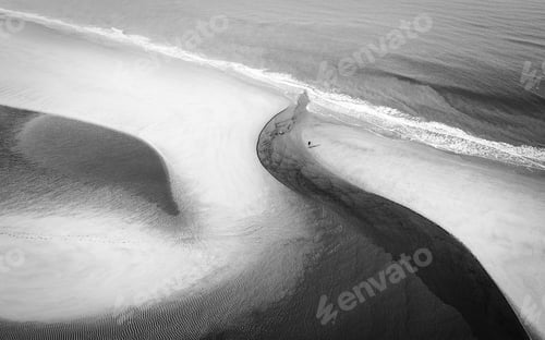 Preview: Aerial greyscale shot of a pathway on the beach near the waves of the ocean