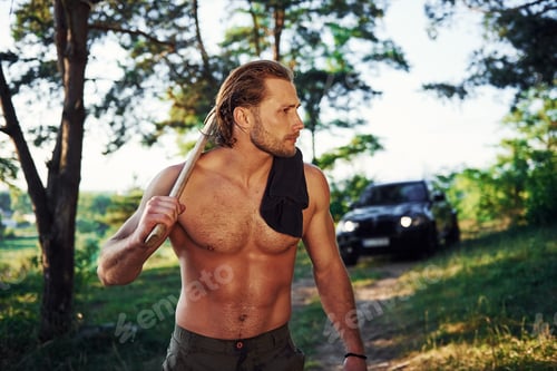 Preview: Handsome shirtless man with muscular body type is in the forest at daytime