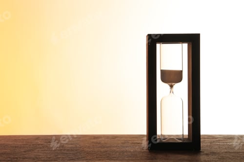 Preview: Hourglass with flowing sand on table against light background. Time management