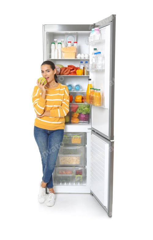 Preview: Young woman eating apple near open refrigerator on white background