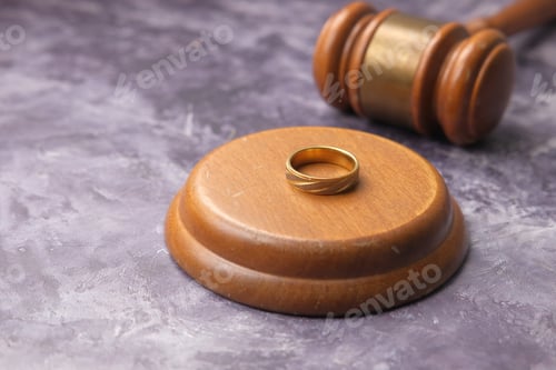 Preview: Divorce concept with gavel and wedding rings on table.