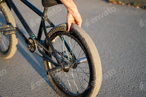 Preview: A BMX bicycle rests on a city street with a flat rear tire,