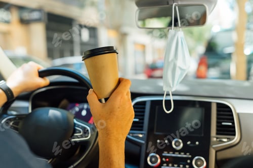 Preview: Drinking coffee in the car, with a mask hanging from the mirror for virus protection