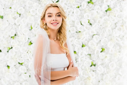 Preview: happy beautiful bride with blonde hair posing at camera on white floral background