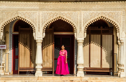 Preview: Indian young woman in front of old colorful door.