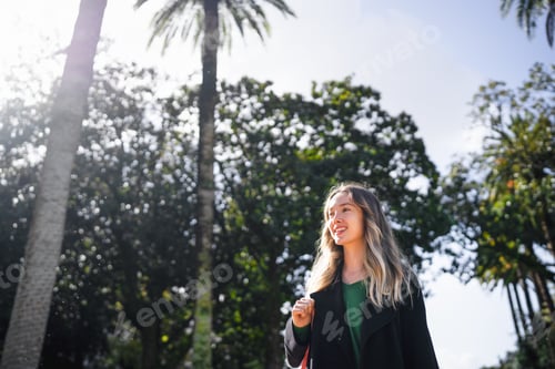 Preview: Young woman smiling walking in sunny park