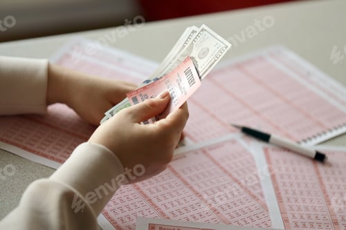 Preview: A young woman holds the lottery ticket with complete row of numbers and dollar bills