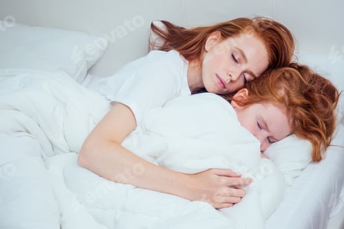 Preview: beautiful redhaired ginger woman hugging asleep her daughter under white blanket