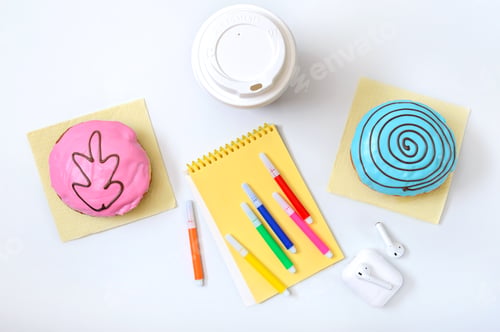 Preview: Berliner donuts, coffee, headphones and materials for creativity on a white office desk.