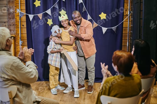 Preview: Happy young African man embracing his two children during performance