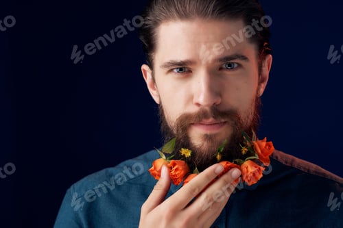 Preview: handsome man with flowers in a beard in a black shirt close-up Studio