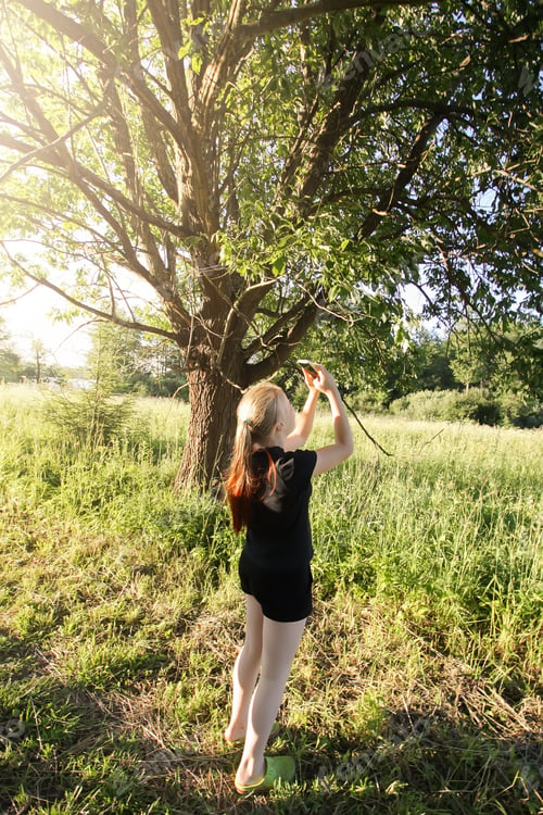 Preview: Teenager girl taking photo of summer nature in countryside.