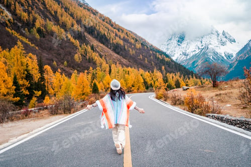 Preview: Young Happiness female tourist enjoying the beautiful autumn scenery while traveling on a road trip.