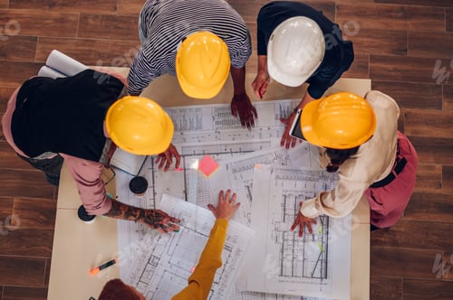 Preview: Multiracial team of architects having a meeting while using blueprints