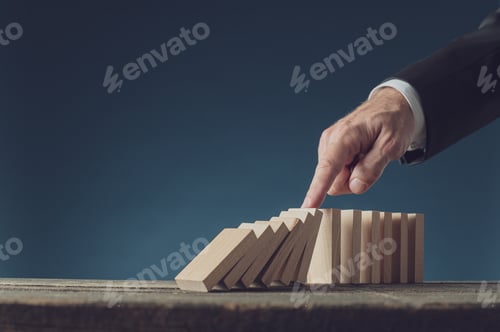 Preview: Business crisis manager stopping collapsing dominos with his finger