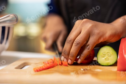 Preview: Close up of black woman chopping red bell pepper on cutting board
