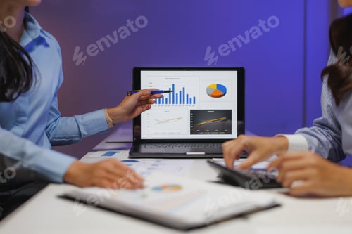 Preview: Businesswomen analyzing financial charts on laptop and using calculator