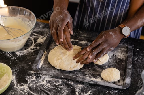 Preview: Hands of african american couple in aprons preparing bread dough in kitchen
