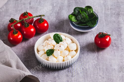 Preview: A bowl of mozzarella balls and spinach on the table