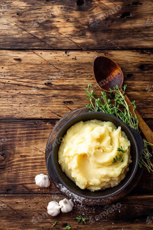 Preview: Mashed potatoes, boiled puree in cast iron pot on dark wooden rustic background, top view