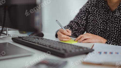 Preview: Asian business women write a summary of their work on a post-it. Business woman