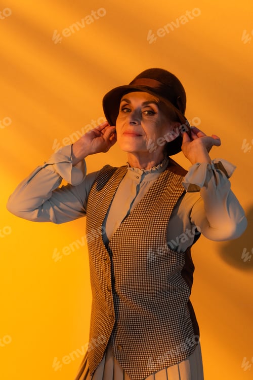 Preview: Stylish elderly woman in vintage hat on orange background