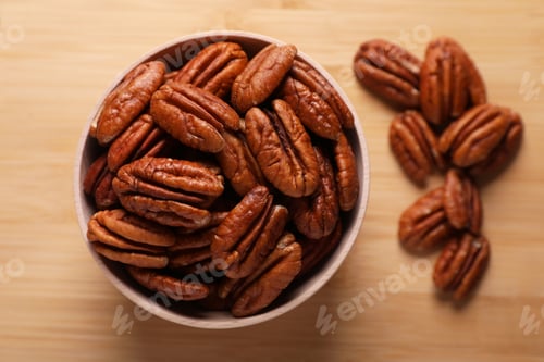 Preview: Tasty pecan nuts with bowl on wooden table, flat lay