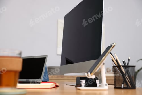 Preview: Stylish workplace with modern computer, other devices and stationery on desk indoors, closeup