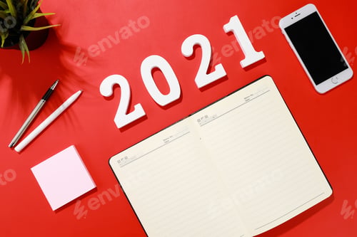 Preview: Flat lay shot of a planner, a smartphone, pens and a houseplant on a red background