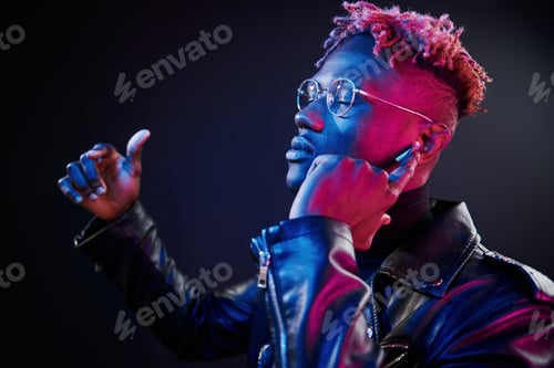 Preview: Listening to the music. Futuristic neon lighting. Young african american man in the studio