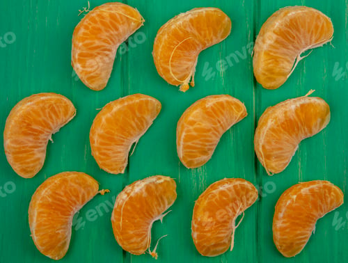 Preview: top view peeled orange wedges on a green background