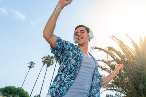 Preview: Handsome young male in headphones enjoying music outdoor on summer resort.