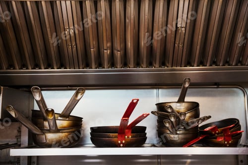 Preview: Close up of stacks of pots and pans on a shelf in a restaurant kitchen.