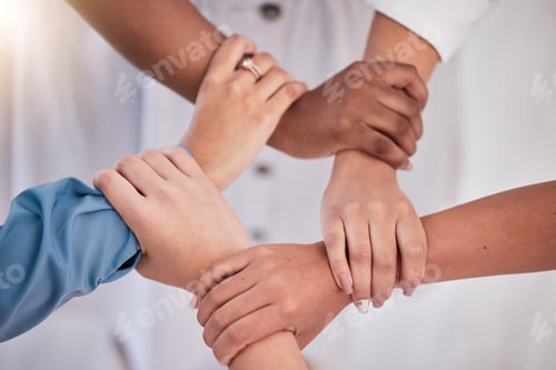 Preview: Diverse colleagues hands holding wrists from above in support of unity, loyalty and teamwork in the