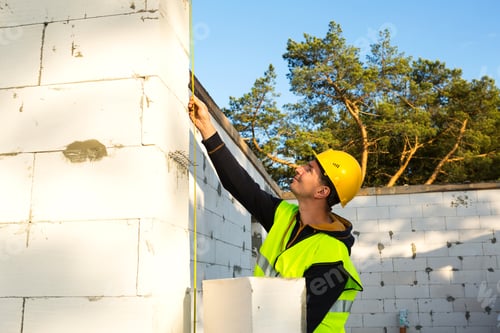 Preview: Construction worker at construction site measures the length of the window opening and the wall
