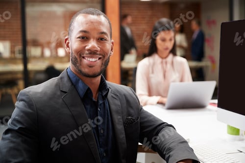 Preview: Portrait Of Businessman Working At Desk On Computer In Open Plan Office