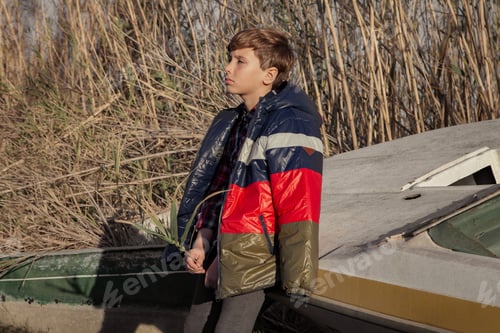 Preview: A thoughtful kid leaning on an abandoned ship during sunset.