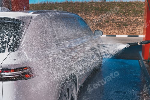 Preview: Сar wash self-service. Man washing luxury vehicle with white foamy detergent.