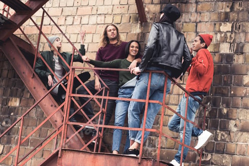 Preview: group of young stylish people standing on stairs of old industrial building