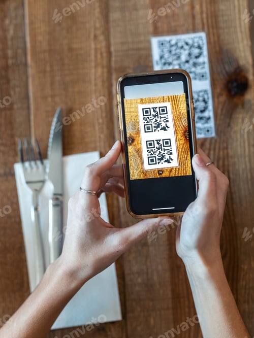 Preview: woman hands using the smart phone to scan the qr code to select food menu in the restaurant.