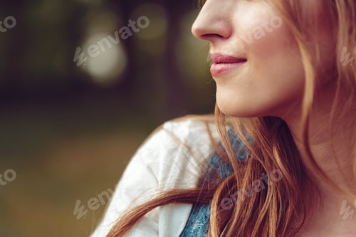 Preview: Woman with long hair enjoying a moment outdoors in a natural setting with blurred background
