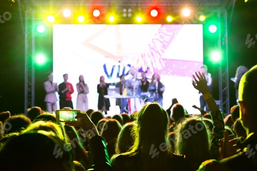 Visualização: Grande multidão de pessoas em holofotes de néon em um show ao ar livre