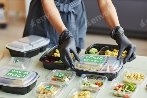 Preview: Woman carefully packing food delivery orders in plastic containers