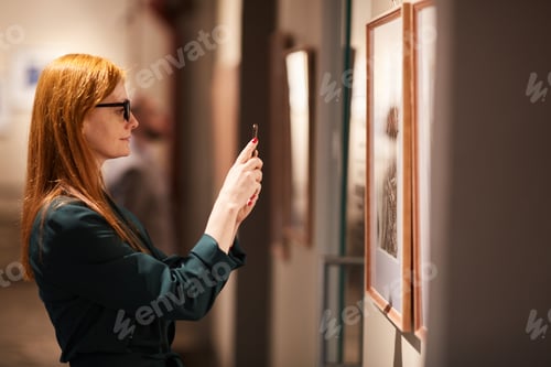 Preview: Woman taking photo of paintings