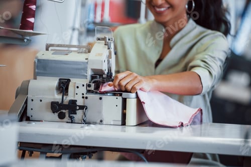 Preview: Dressmaker woman sews clothes on sewing machine in factory